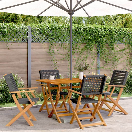 5 piece black poly rattan garden dining set with solid wood chairs under an umbrella in a lush outdoor setting.