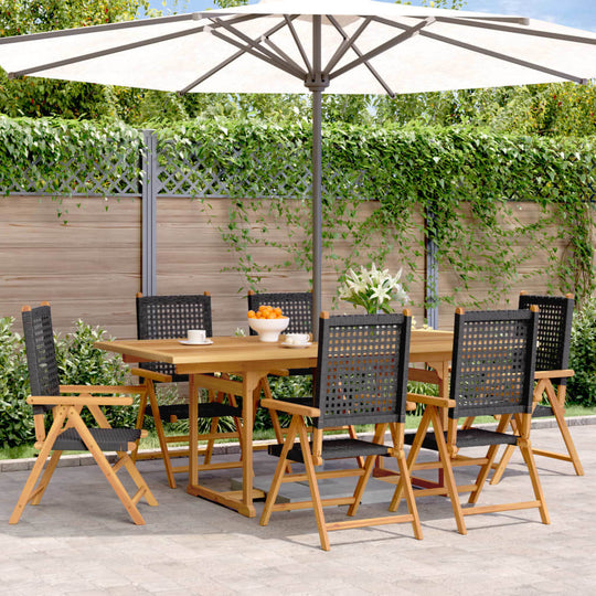 7 Piece garden dining set with black poly rattan chairs and solid wood table under an umbrella in a lush outdoor setting.