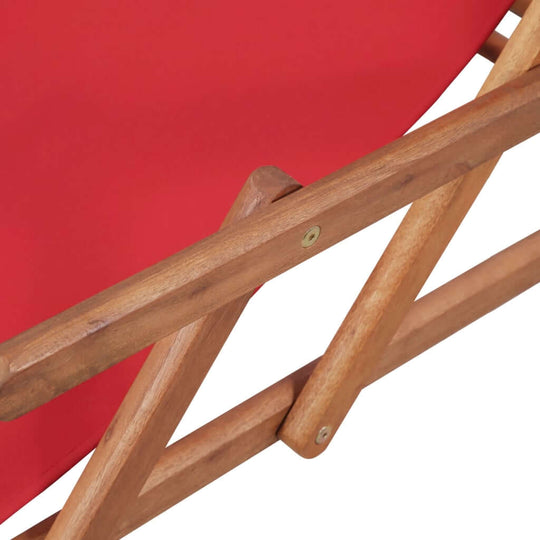 Close-up of the wooden frame of a folding beach chair with red fabric seat, showcasing sturdy construction and adjustability.