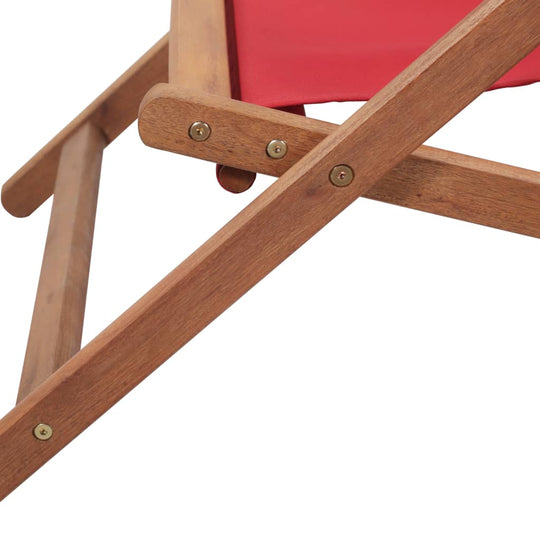 Close-up of a folding beach chair showing wooden frame and red fabric seat for comfort and stability.